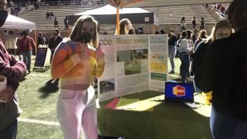 Alana in front of CCE's poster at Sunset Fest