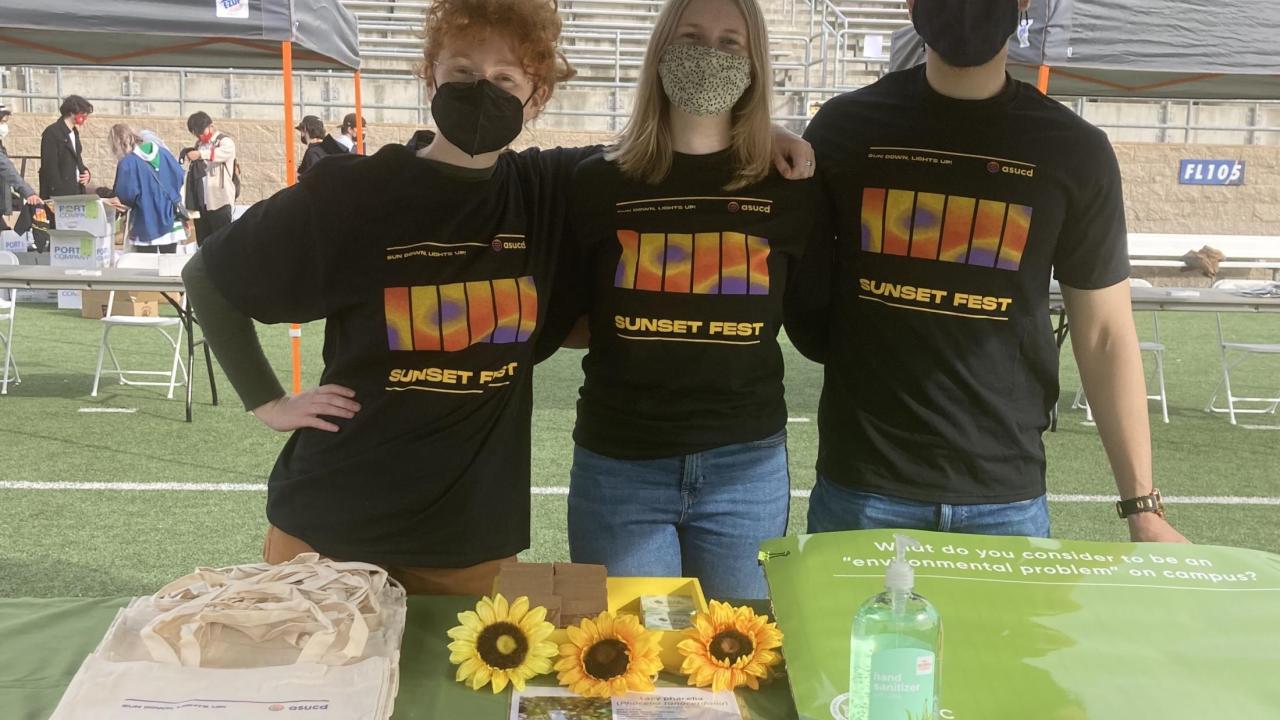 Holly, Sydney, and Arthur standing behind EPPC's table at the ASUCD Sunset Fest
